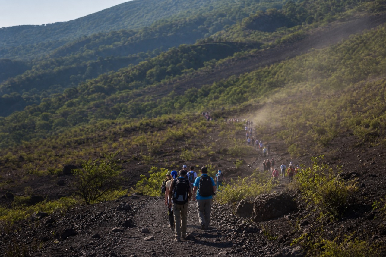 A group of hikers gathering with local guides at the Santa Ana Volcano trailhead in morning light